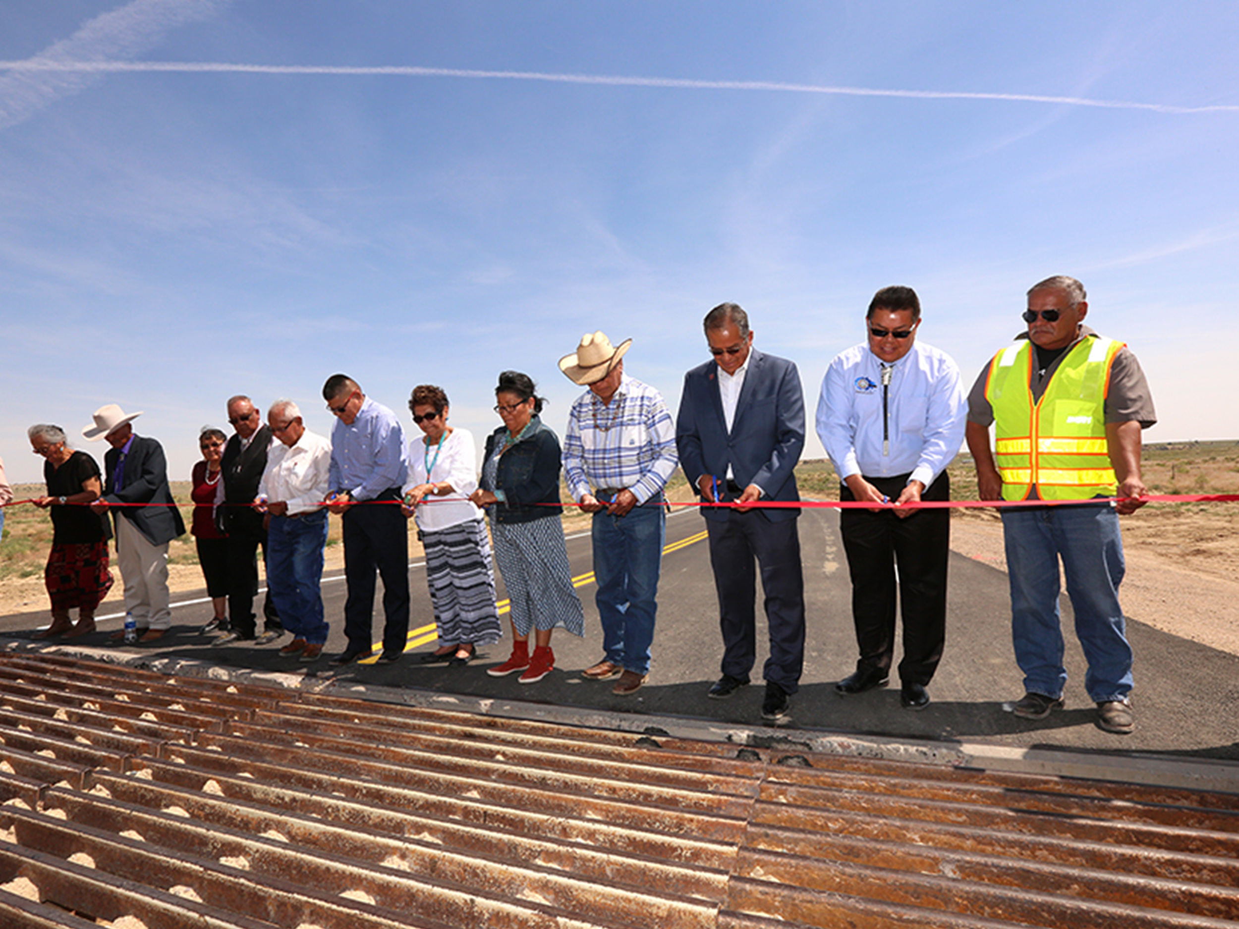 Local officials gather near a newly installed cattle grate to cut the ribbon on the Littlewater Chapter House Road project.
