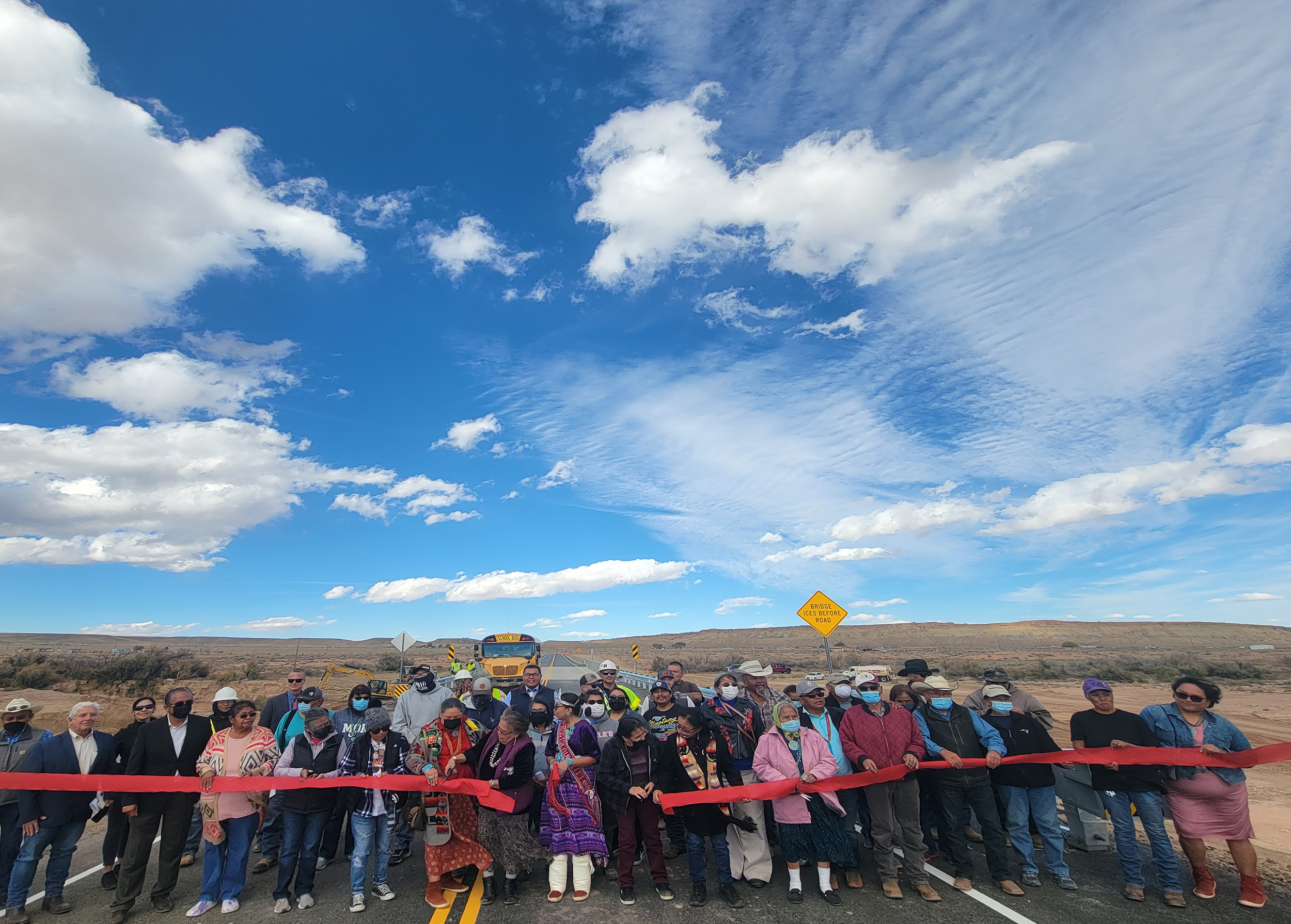 Local community members and officials gather to cut the ribbon on the newly constructed Sanostee Bridge.