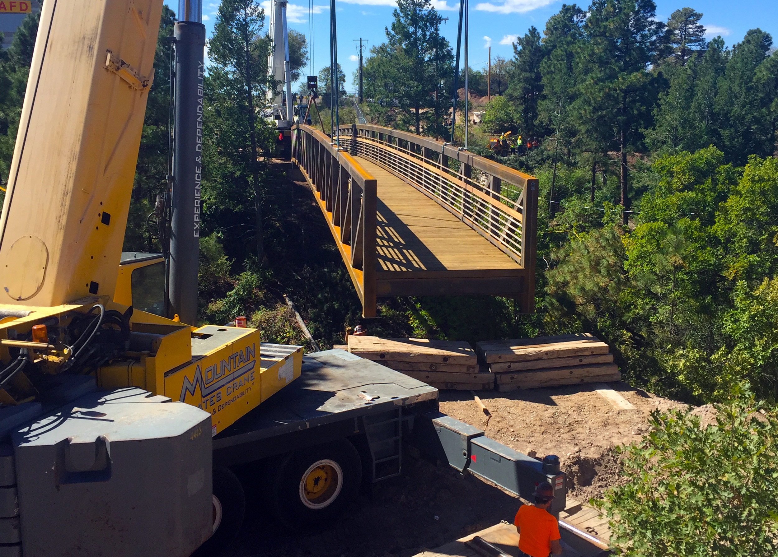 Cranes working in unison to set the pedestrian bridge onto the abutments.