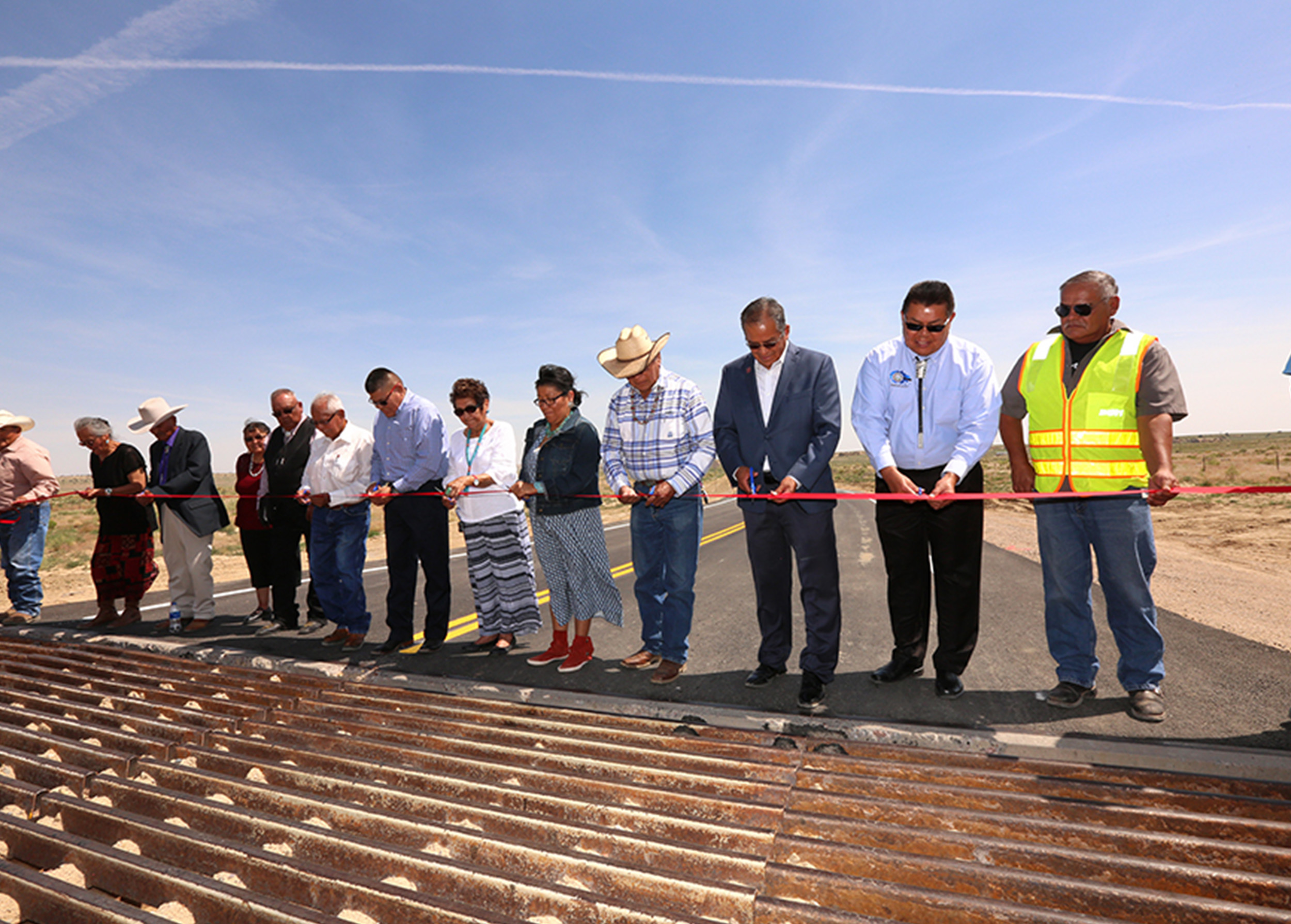 Local officials gather near a newly installed cattle grate to cut the ribbon on the Littlewater Chapter House Road project.