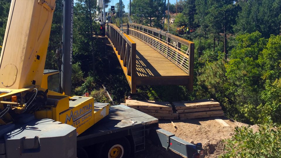 Cranes working in unison to set the pedestrian bridge onto the abutments.