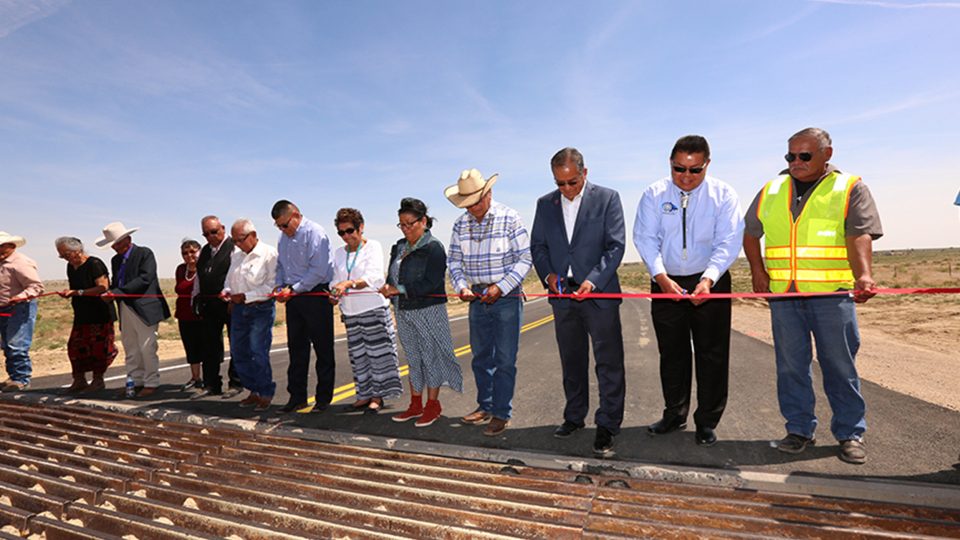 Local officials gather near a newly installed cattle grate to cut the ribbon on the Littlewater Chapter House Road project.